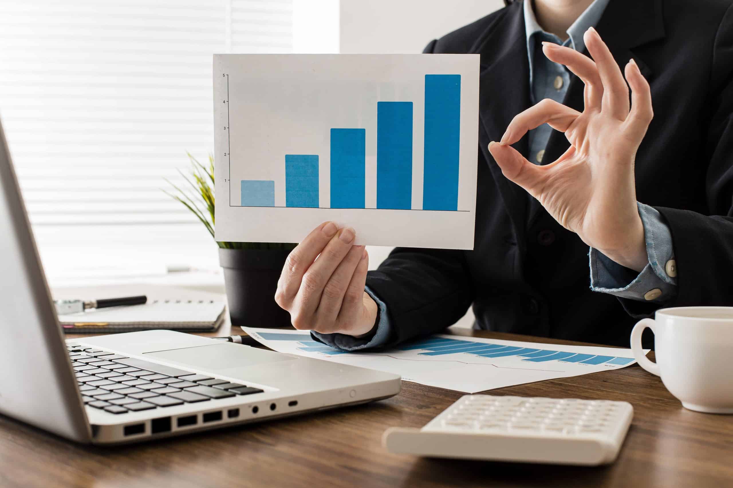 businessman doing ok sign while holding growth chart scaled